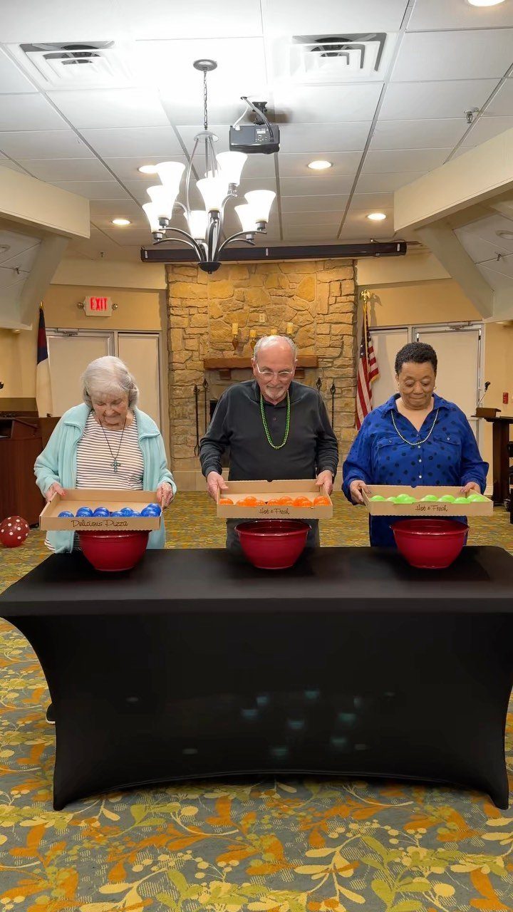 Three seniors playing a game with colorful balls at a black table.