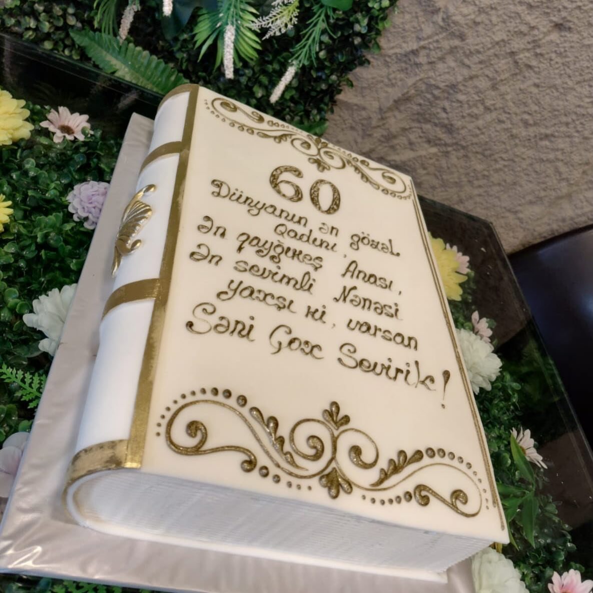 Book shaped white cake with gold lettering and number 60 on the cover.