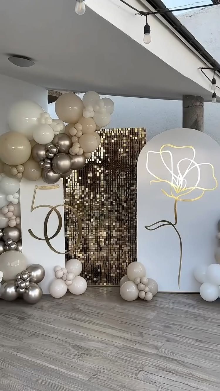 Gold number 50 decoration with white and gold balloons and sequin backdrop.
