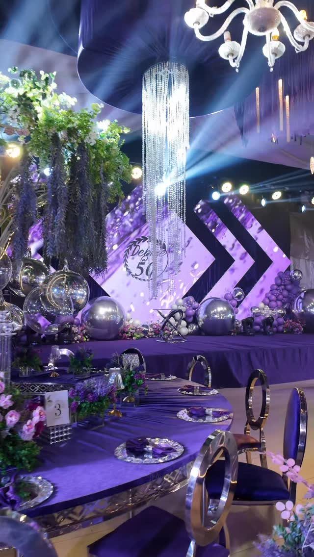 Purple and silver 50th birthday party decoration with crystal chandeliers and floral arrangements