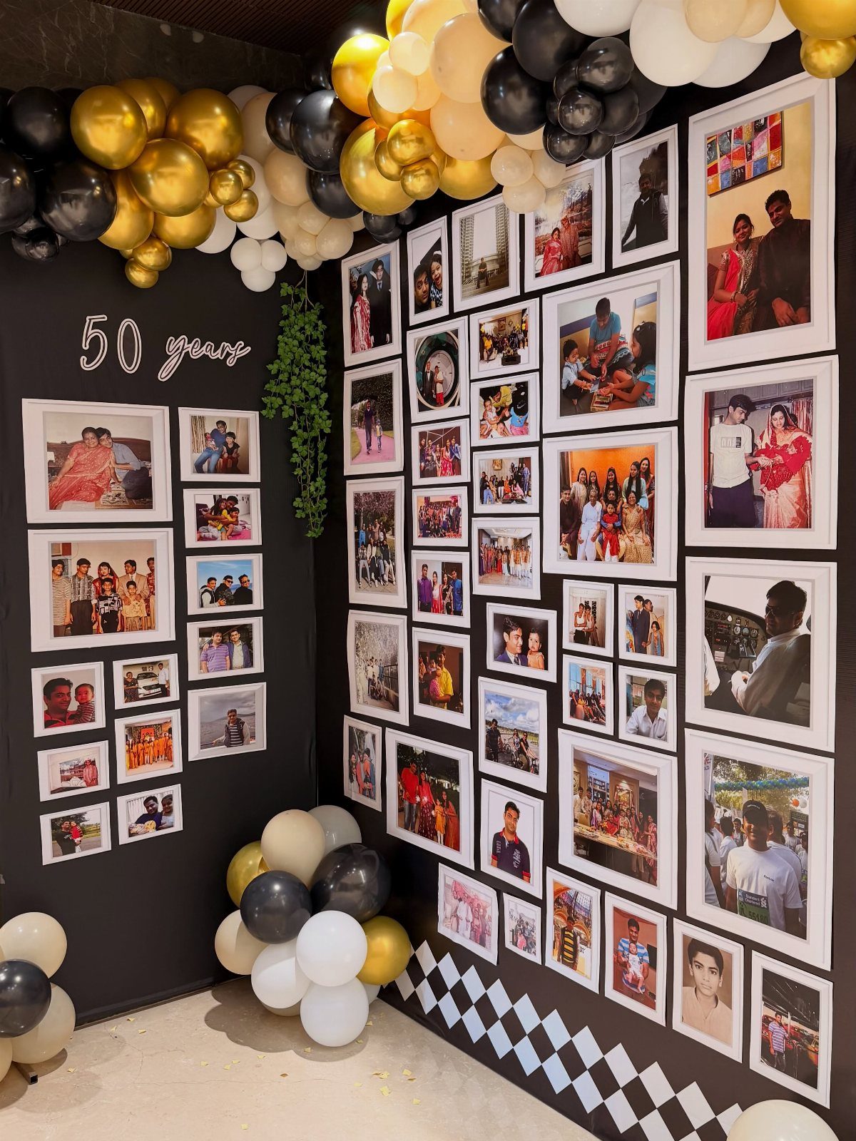 Photo wall with framed pictures and balloons for a 50th birthday celebration.