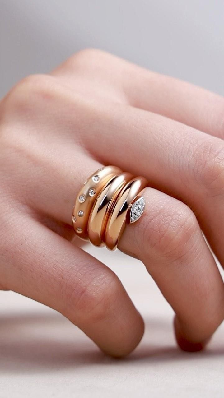Four rose-gold stackable rings with diamonds worn on a person's finger.