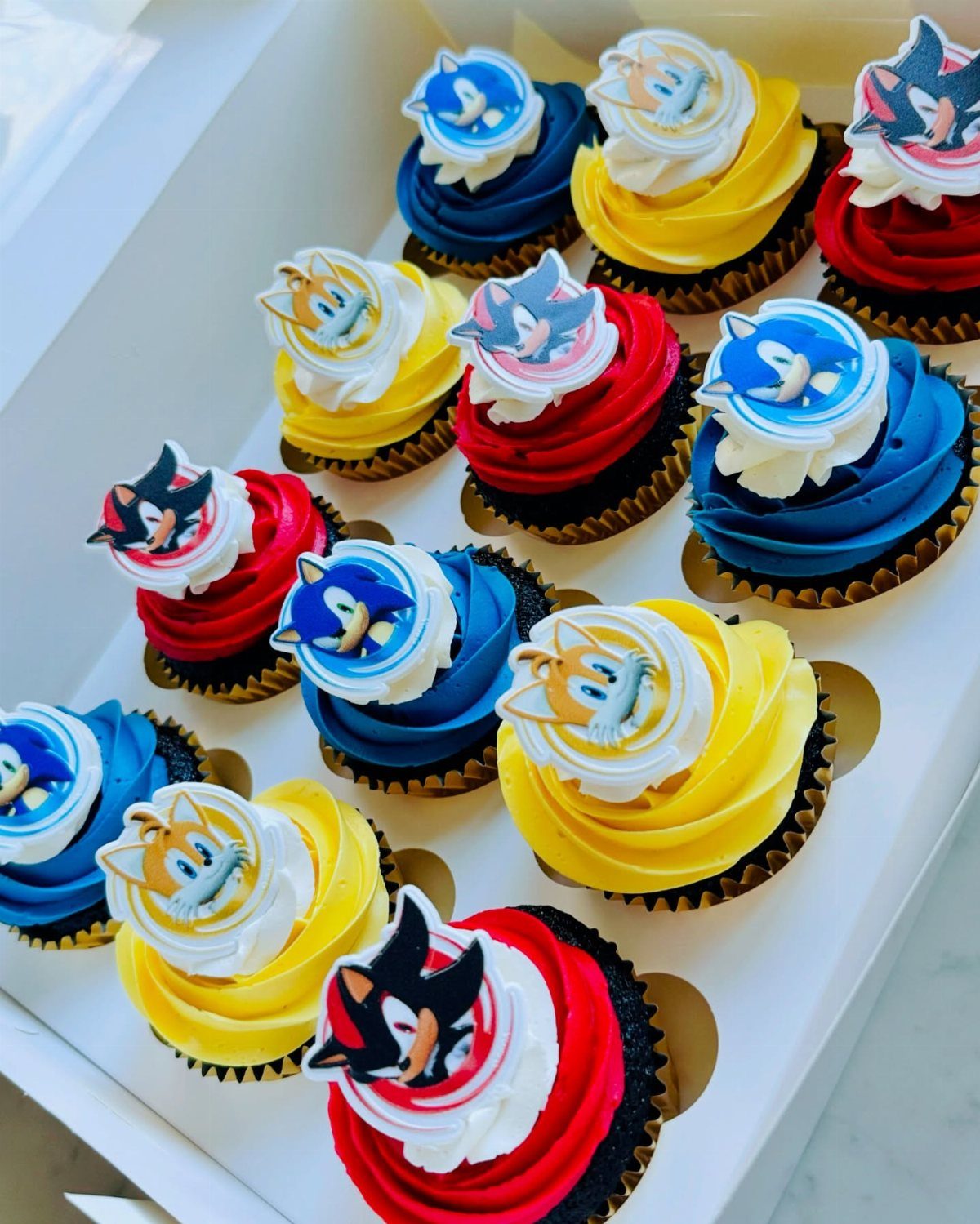 Cupcakes with red, blue, and yellow frosting topped with Sonic character cutouts.