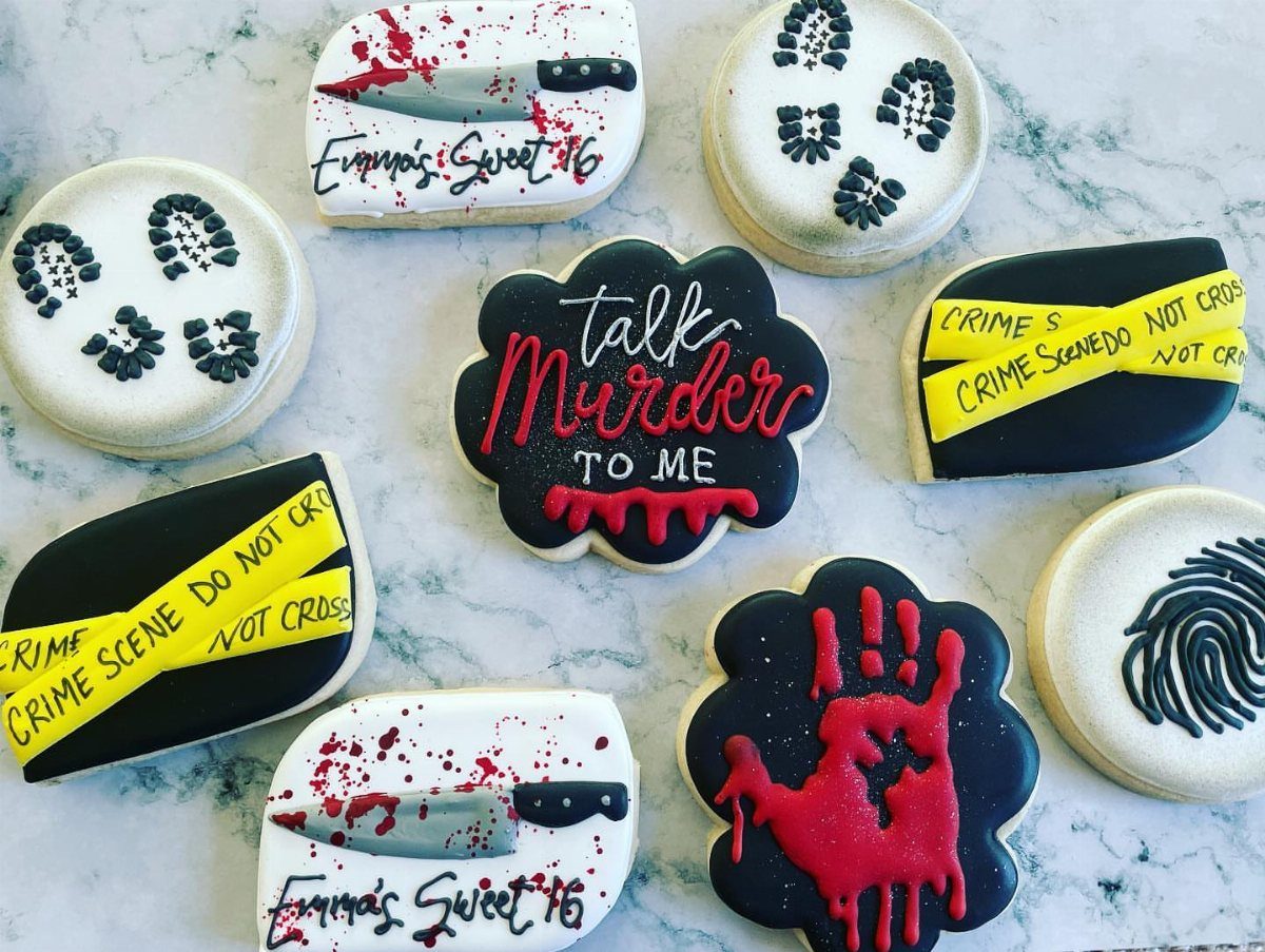 Murder mystery themed sugar cookies with crime scene tape and bloody knives.