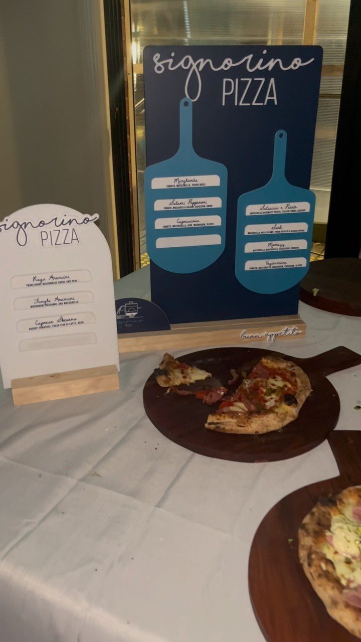 Pizza slices on wooden boards with Signorino Pizza menu signs on white tablecloth