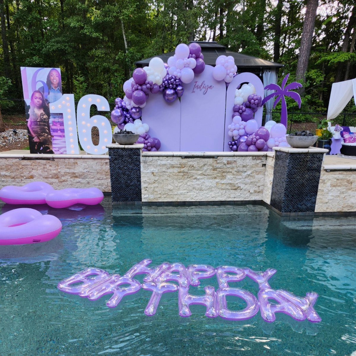 Swimming pool decorated with purple balloons, floats, and a large white 16 sign.