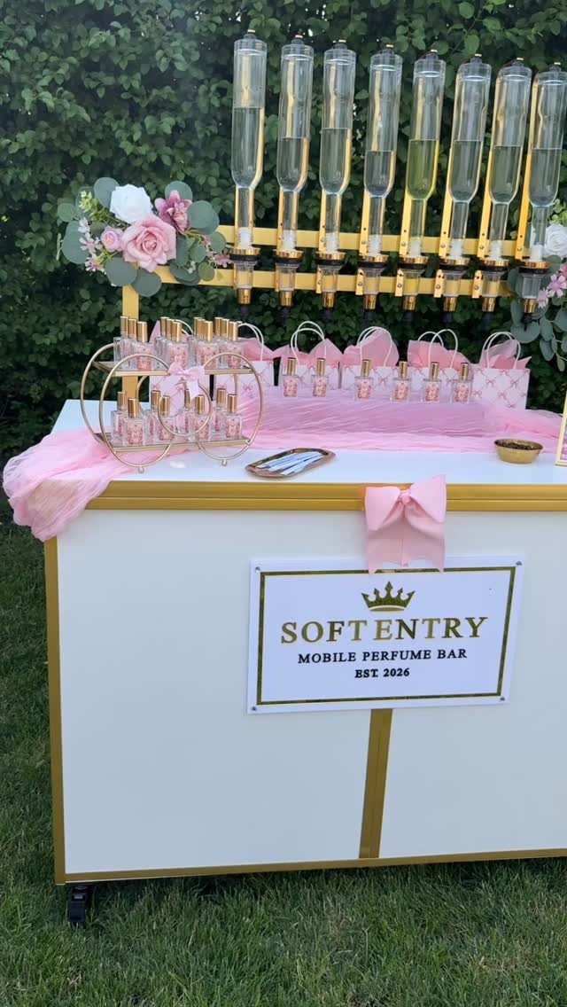 Mobile perfume bar with gold accents and pink decor set outdoors by greenery