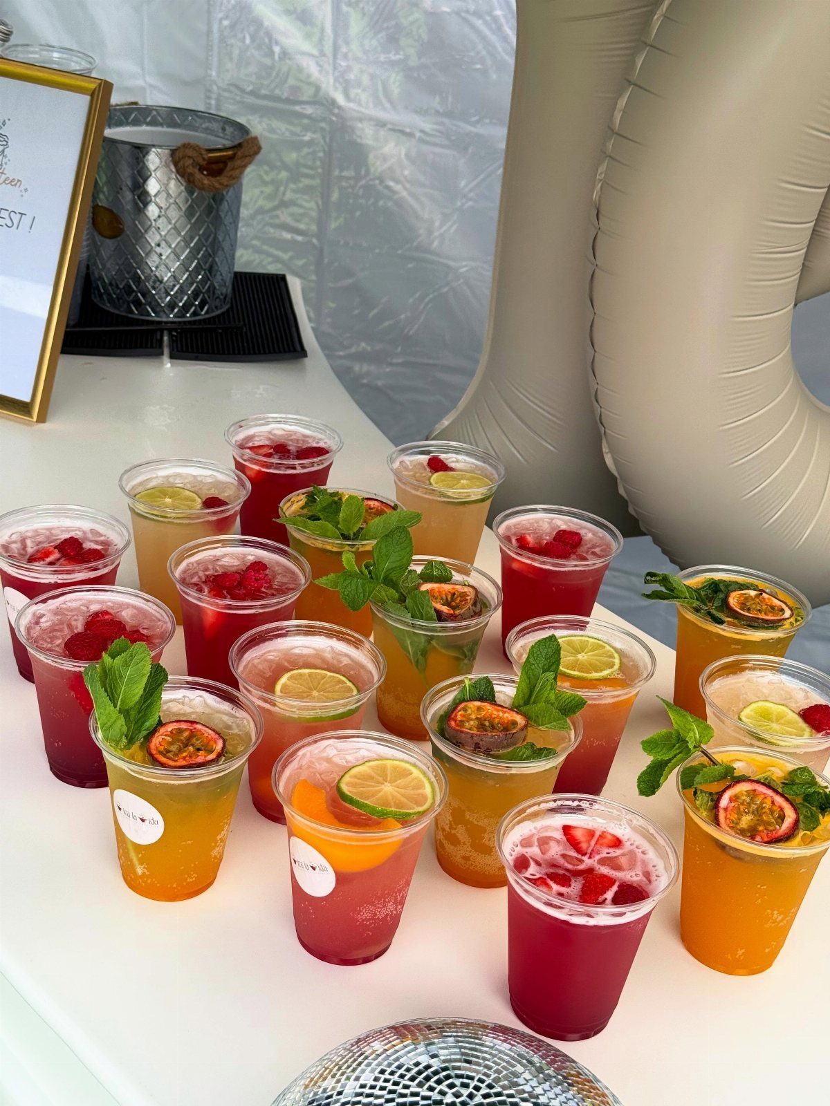 Colorful fruit-infused drinks with mint and citrus slices on a white table.