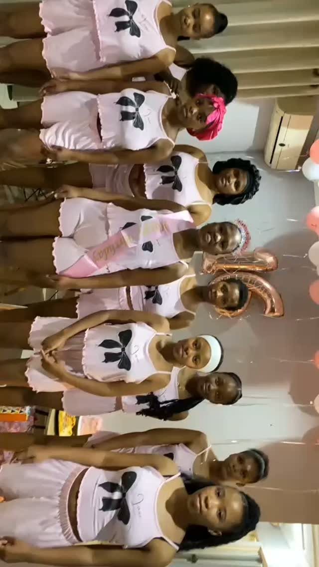 Group of young women in matching pink pajamas posing for a party photo.