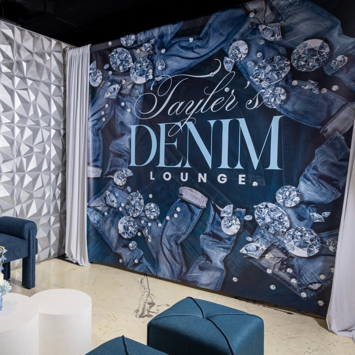 Denim lounge backdrop with diamonds and text in a modern event space.