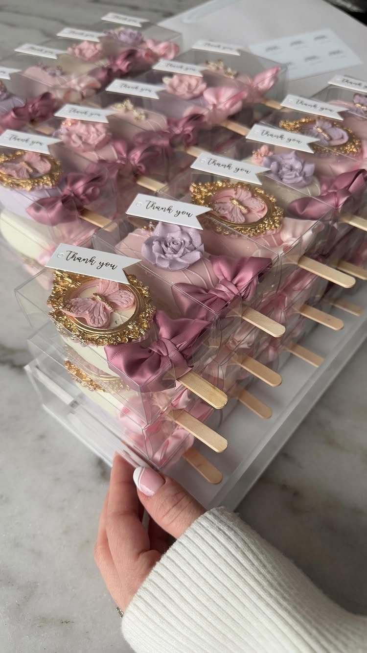 Small pink and purple gift boxes with thank you tags in a clear tray