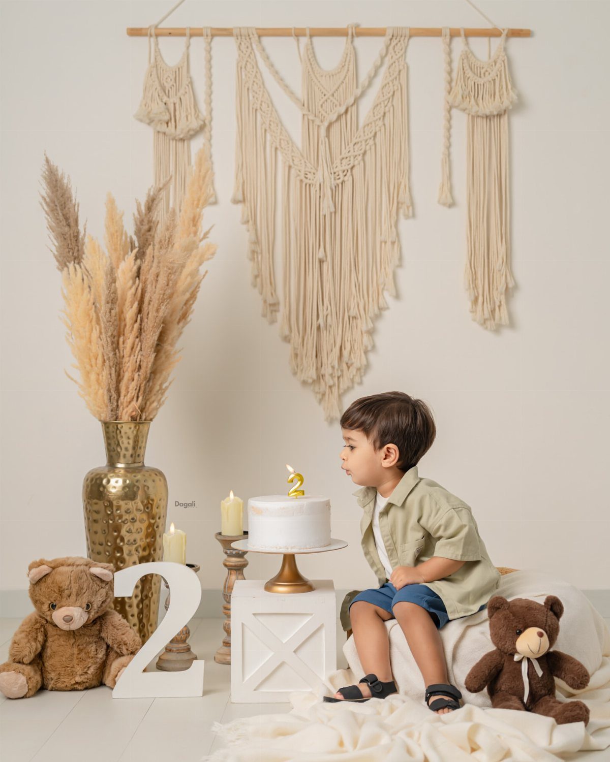 Young boy sitting by a birthday cake and large number two decoration