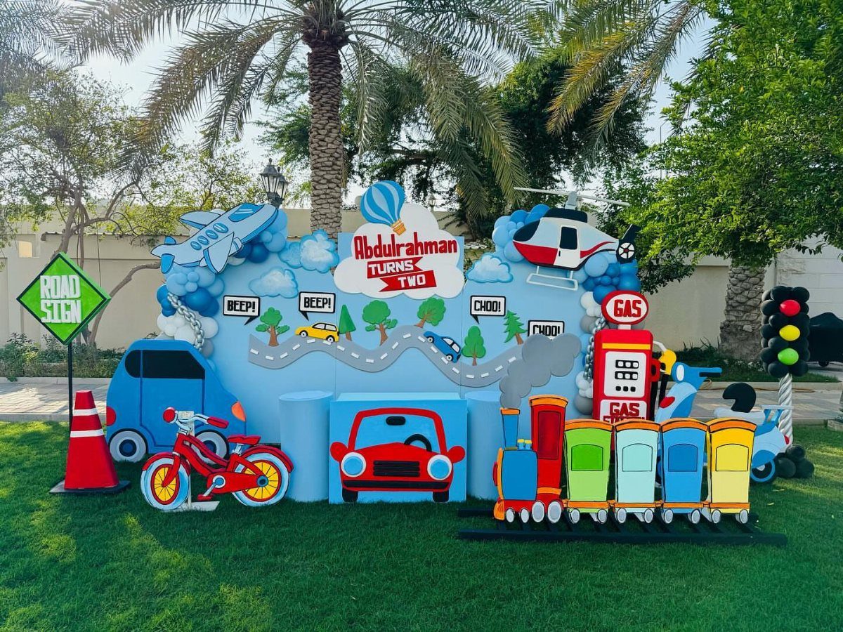 Transportation themed birthday party setup with a colorful train, cars, and airplanes.