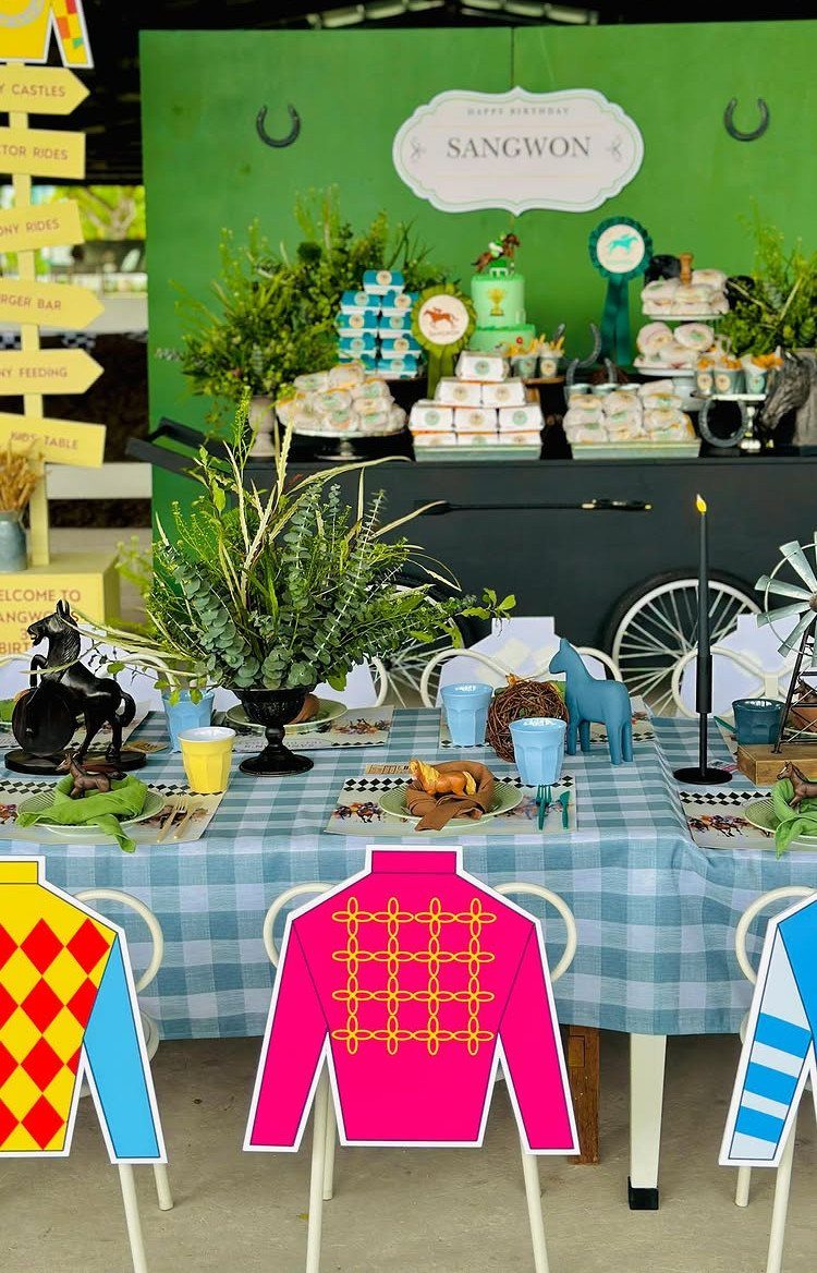 Horse racing themed birthday party table with jockey jersey chair decorations and desserts.