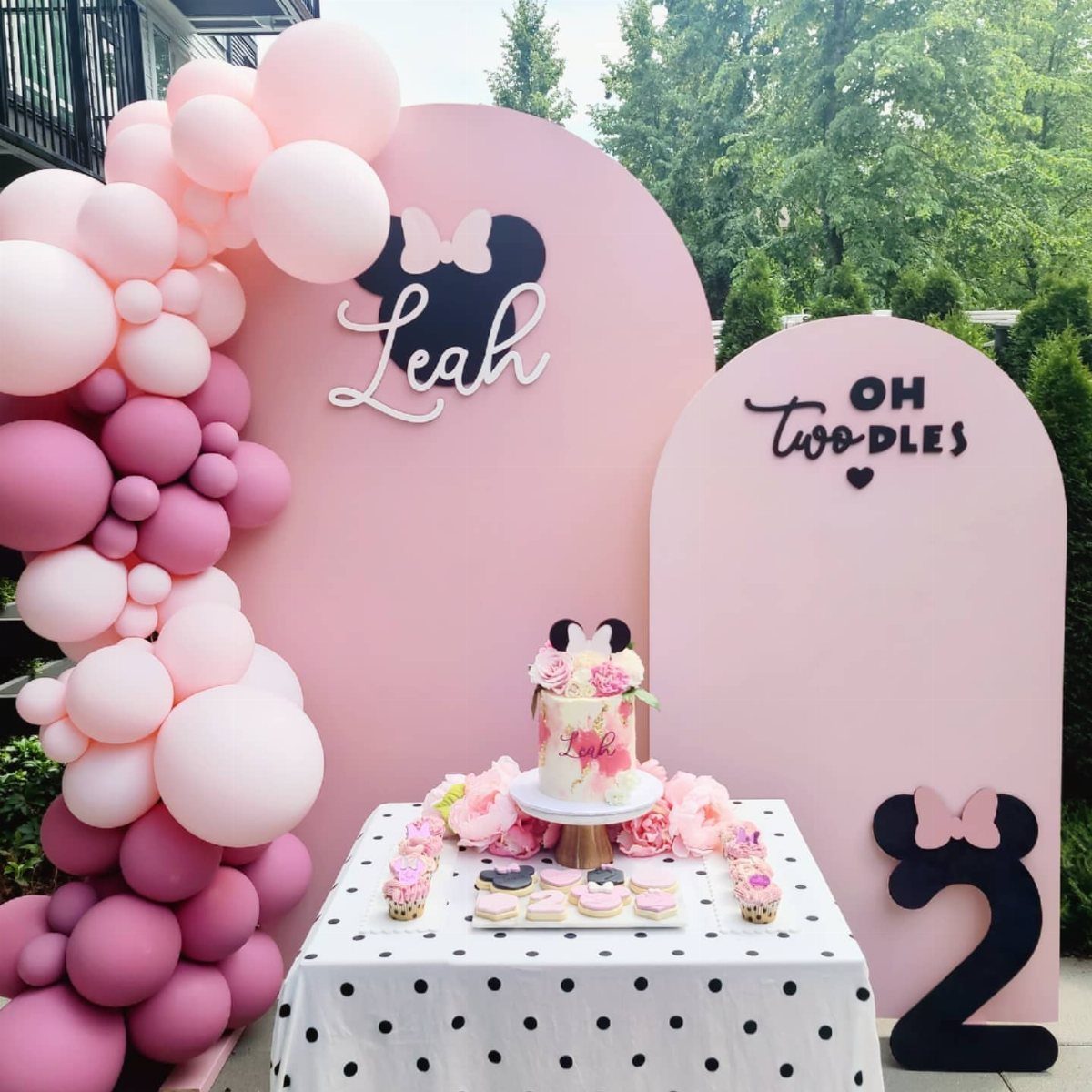 Minnie Mouse themed second birthday party setup with pink balloons and cake.