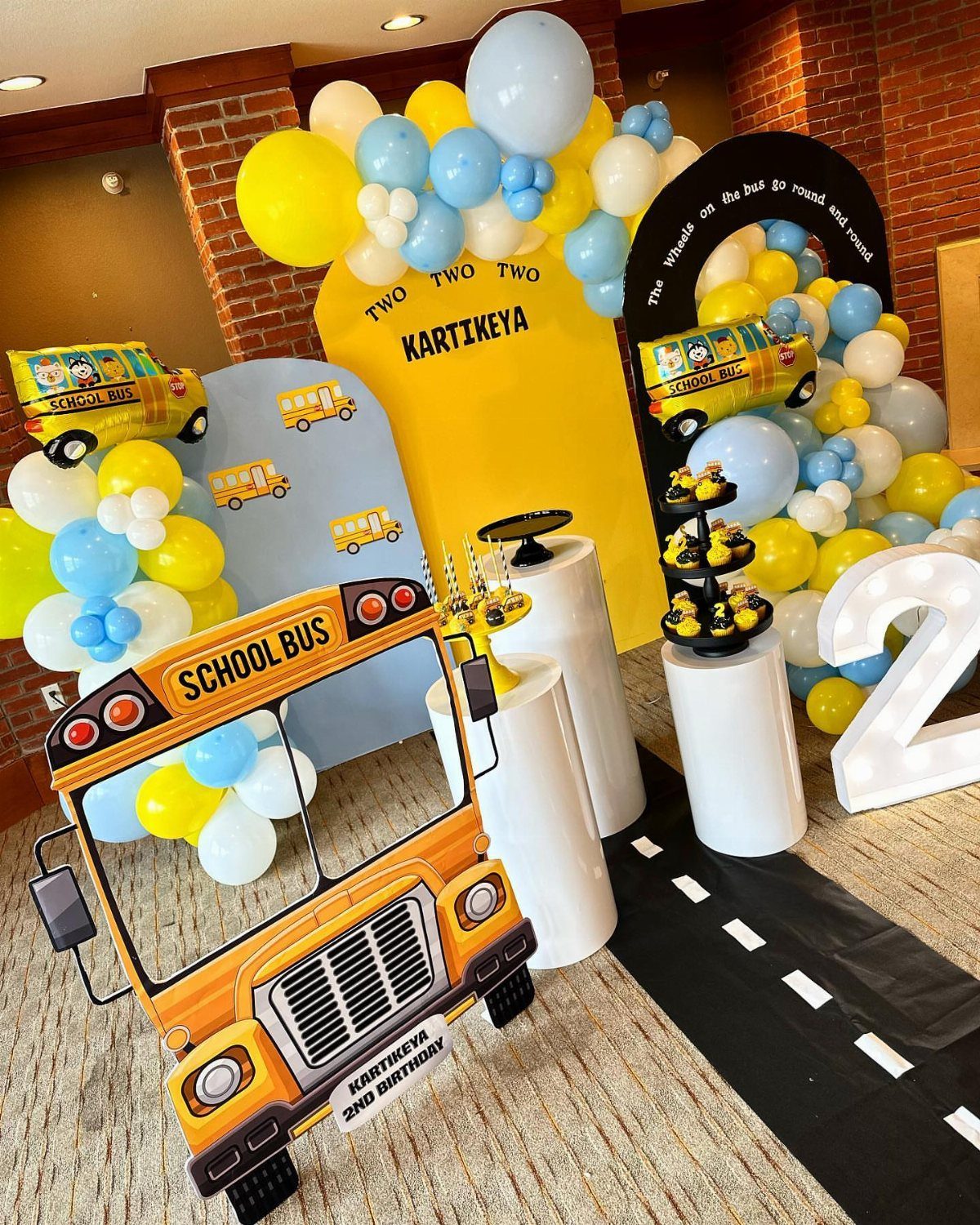 School bus themed second birthday party decorations with yellow balloons and a large number two.