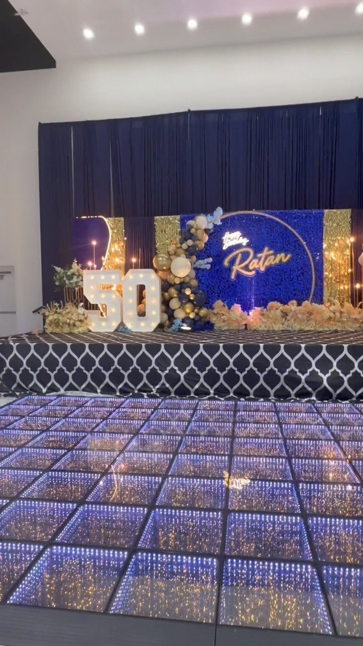 Upscale event venue with glowing 50 numbers, blue backdrop, and illuminated dance floor.