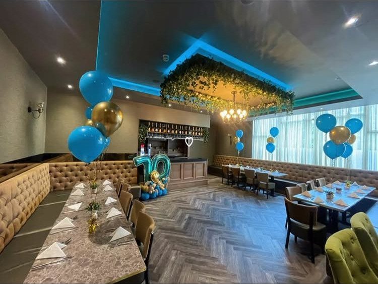 Restaurant interior decorated with blue and gold balloons for a 70th birthday party.