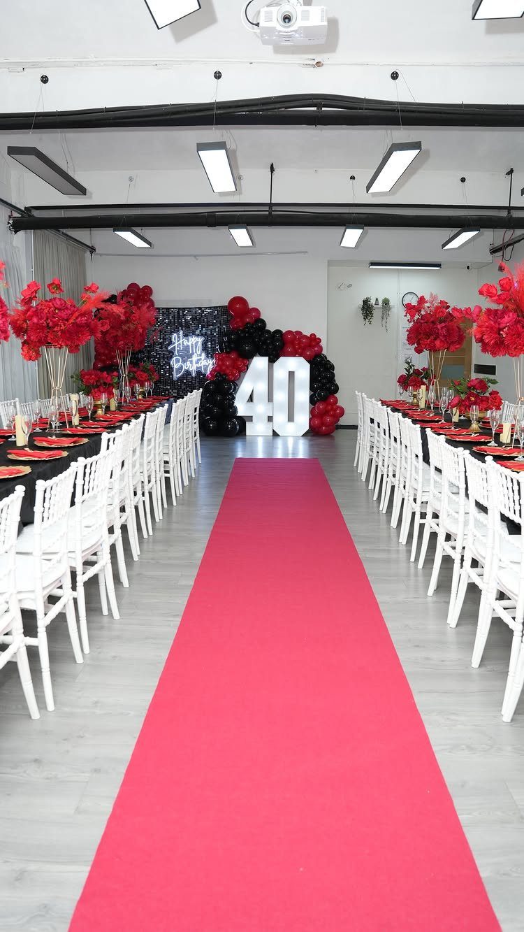 Event venue decorated with red carpet, long tables, and 40th birthday balloons.